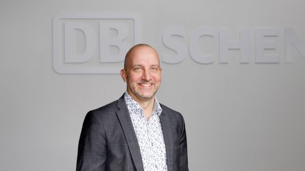 Joni Lehtonen seisoo DB Schenker -kyltillä varustetun seinän edessä.