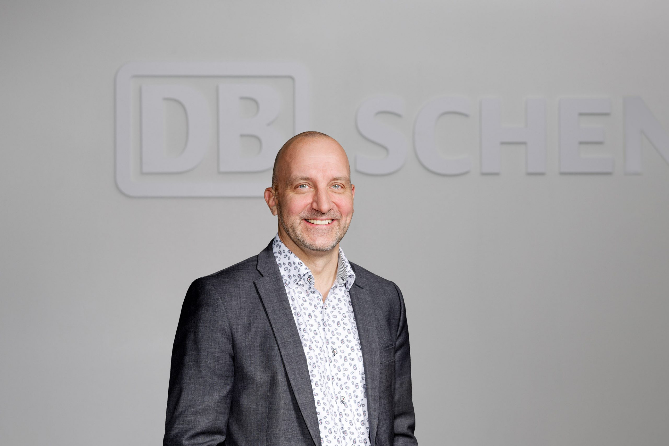 Joni Lehtonen seisoo DB Schenker -kyltillä varustetun seinän edessä.