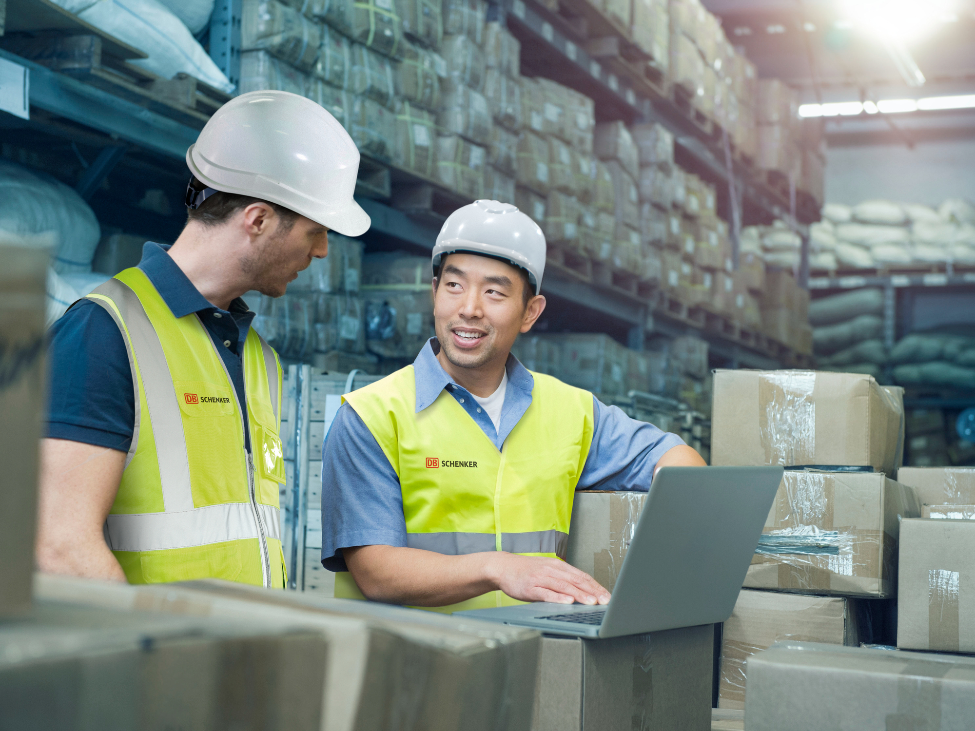 Varastotyöntekijät käyttävät tietokonetta lähetysten keskellä.