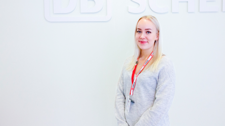 Niina Putkonen seisoo DB Schenkerin kyltin edessä ja katsoo kameraan