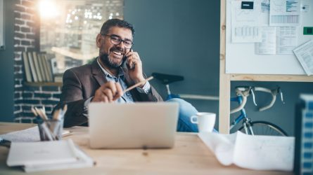 Mies istuu pöydän ääressä tietokone edessään