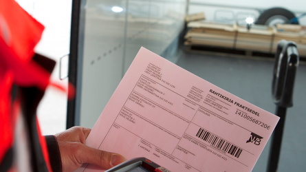 Paperinen rahtikirja kuljettajan kädessä. Kuljettaja skannaa viivakoodin.