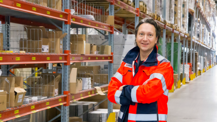 Tommi Saira seisoo varastohyllyjen edessä.