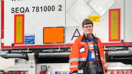 Heli Hörkkö seisomassa ajoneuvon takana kädessään oranssikilppi.