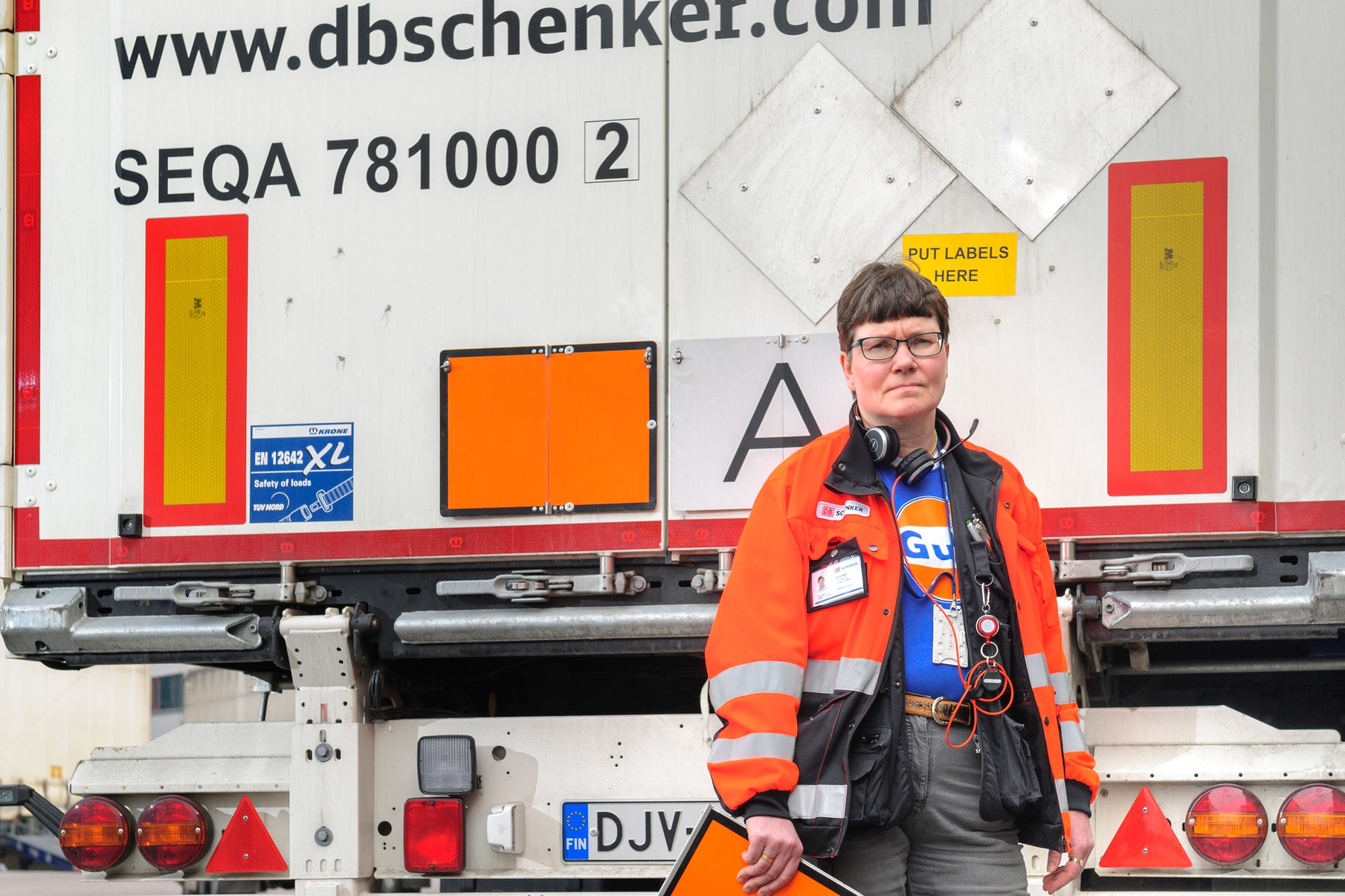 Heli Hörkkö seisomassa ajoneuvon takana kädessään oranssikilppi.